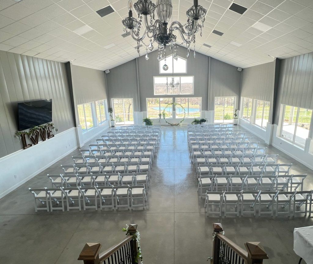 Wedding venue near Tulsa, OK set up for 150 guest with white chairs facing big pond through huge windows with scenic skyline views 