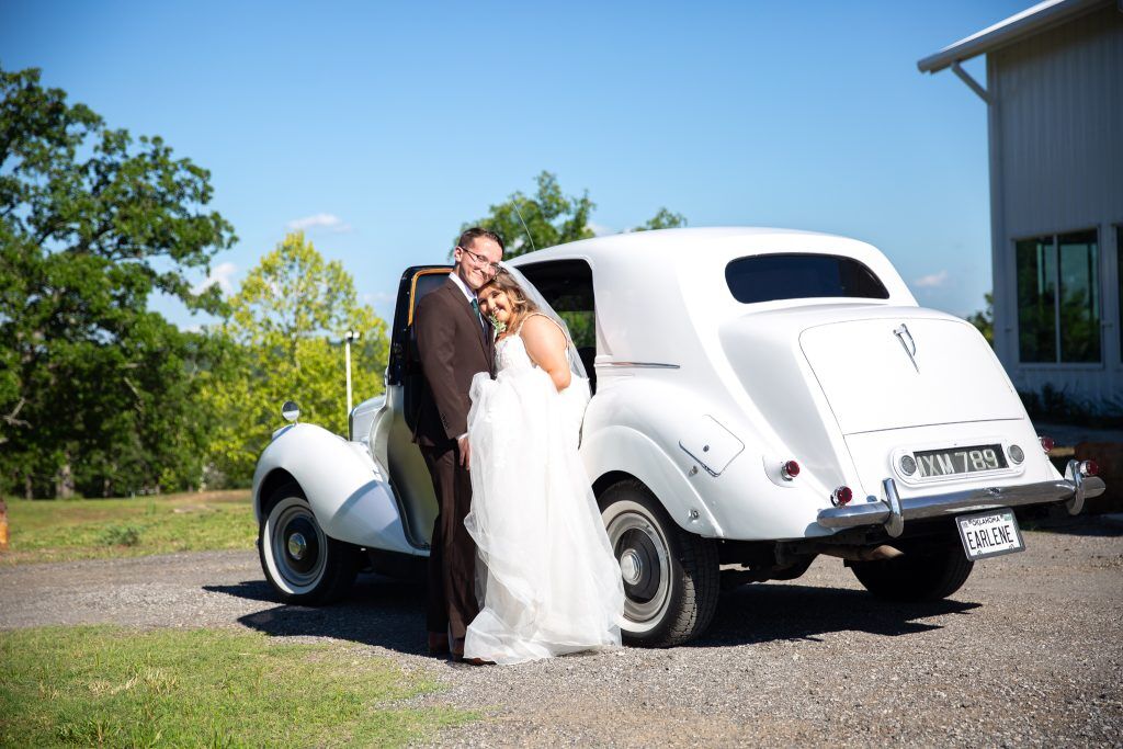 Lovely wedding near Tulsa, OK with couple standing in front of their white get away coupe