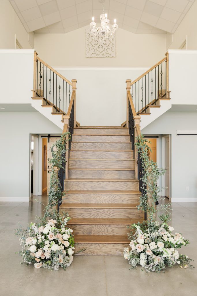 breautiful wooden stair way with landing and divided stair directions with big flower bouquets at the base